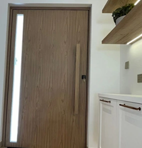 An interior wood-tone door with a slim vertical glazed detail.