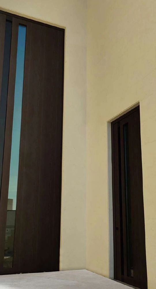A tall wood-tone entrance with a narrow vertical glazed panel and a coordinated smaller side door.